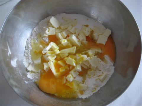 Intanto che il grano si raffreddi prepariamo la pasta frolla. In un'ampia ciotola aggiungere la farina setacciata, lo zucchero, il pizzico di sale, il burro tagliato a pezzetti (tenuto precedentemente a temperatura ambiente), le uova intere e la scorza grattugiata del limone.