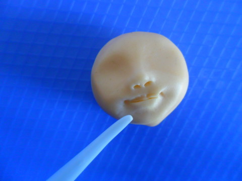 Con uno stecchino incidete due puntini agli angoli della bocca mentre sotto il labbro inferiore appiattite la pasta di zucchero, in modo che il labbro sporga un pochino