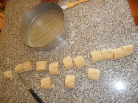 Con un coltello tagliare la pasta a fette di massimo 3 - 4 cm. Prendere ogni singola fetta e chiudere delicatamente la parte inferiore spingendo verso l'esterno la pasta. Questo passaggio serve per ottenere la classica forma della rosellina.