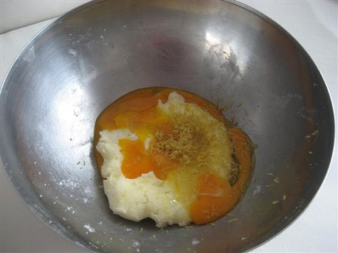 Aggiungere il pizzico di sale, i tuorli, l'uovo intero, la vanillina e la scorza grattugiata di limone.
